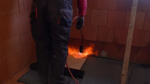Worker applies torch-on waterproofing membrane to corner of interior wall and Stock Footage 311418666