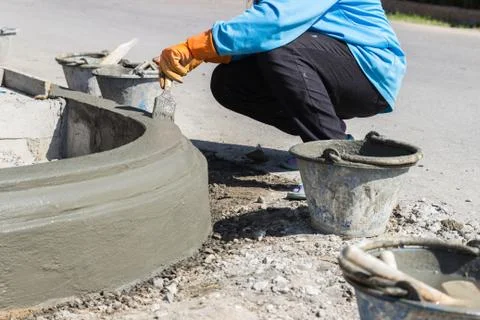 The worker apply cement over the surface of footpath edge Stock Photos