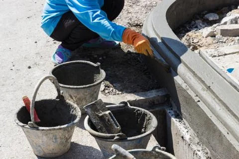 The worker apply cement over the surface of footpath edge Stock Photos