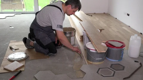 Worker apply glue adhesive on floor for parquet board laying Stock Footage 118198258