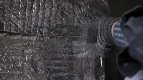 Worker applying adhesive tape on foil insulation seam Stock Footage 315957666