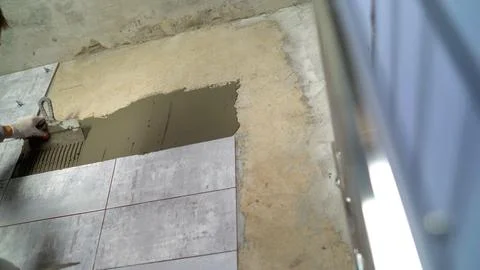 Worker applying adhesive to wall for tiling installation Stock Photos