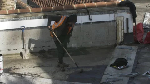 Worker Applying Bitumen Mastic On Roof Flat Of Building In London. Locked Stock Footage 149300492