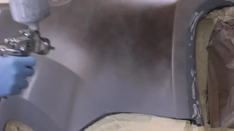 Worker applying brown paint to car body part Stock-Footage 130576550