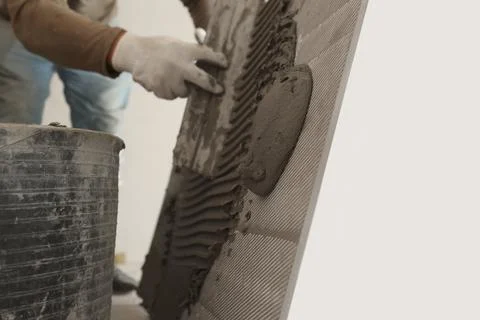 Worker applying cement on wall tile for installation indoors, closeup Fotos de archivo
