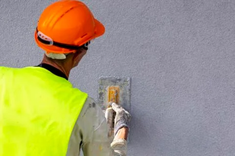 Worker applying decorative plaster on wall Stock Photos