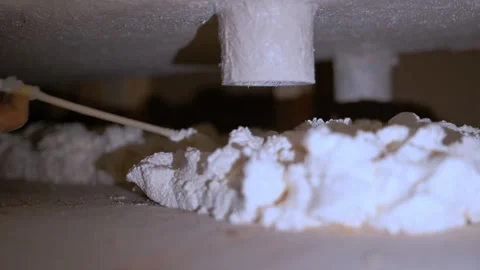 Worker applying expanding foam insulation under a structure. Construction or Stock Footage 332185914