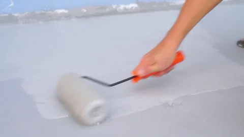 Worker applying grey waterproof coating to a flat surface with a paint roll.. 스톡 동영상 332323202