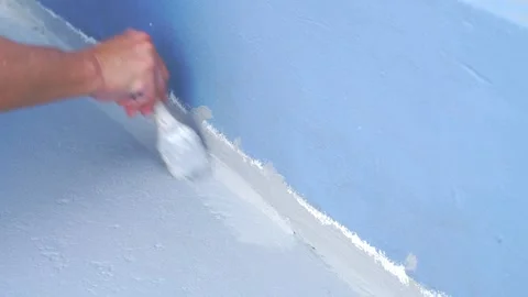Worker applying grey waterproofing sealant or paint to the joint between a .. Stock Footage 332323196