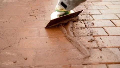 Worker applying grout to brick paving patio Stock Photos