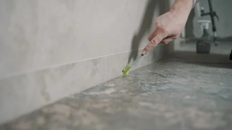 Worker applying grout to tile edges in home renovation project Stock Footage 317381013