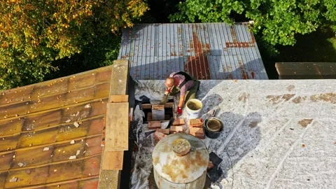 Worker applying mortar layer in chimney construction on flat roof with tar Stock Footage 327274937