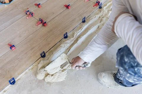 Worker applying mortar for new floor tiles installation Stock Photos