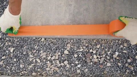 Worker applying orange tape on concrete step with gloved hands Stock Footage 341400707