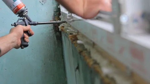 Worker is applying polyurethane foam to fill gap between sash and window frame. Stock Footage 113602638