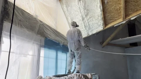 Worker applying polyurethane foam insulation to attic ceiling Stock Footage 323409912
