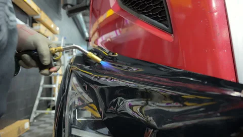 Worker is applying a PPF film with a heating to a red truck. Close up footage of 스톡 동영상 294961895