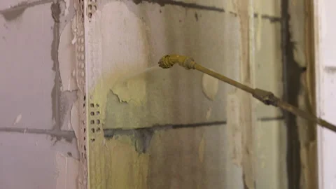 Worker applying primer to wall with spray gun during renovation Stock Footage 342613301
