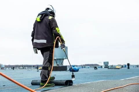 Worker Applying Roofing Material with Torch on Flat Rooftop Stock Photos