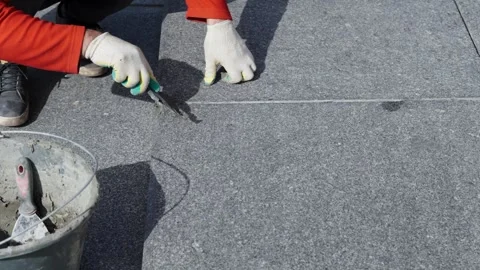 Worker Applying Sealant Along Asphalt Roof Joint With Trowel Stock Footage 347324035