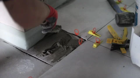 Worker applying tile adhesive on floor before tile installation Stock Footage 314236215