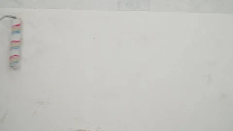Worker applying wallpaper glue to a white wall with a roller during home Stock Footage 348073573