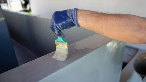 Worker Applying Waterproof Coating to Concrete Parapet With Brush Stock Photos