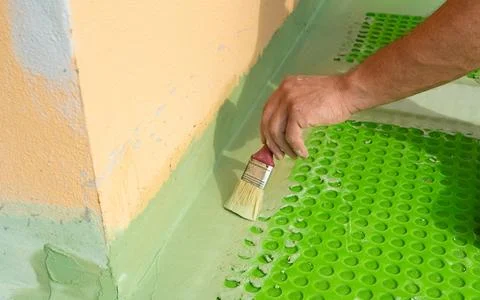 Worker Applying Waterproofing Membrane at Wall and Floor Junction Photos