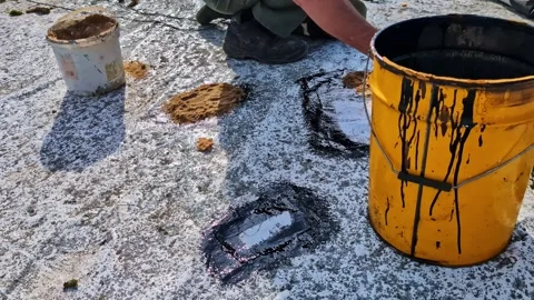 Worker applying waterproofing sealant on flat rooftop surface during roof Stock Footage 327276643
