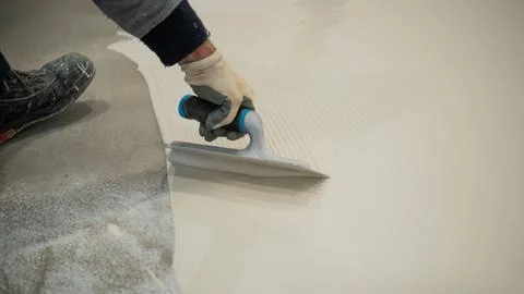 Worker Applying White Liquid Floor Coating With Roller and Trowel Stock Photos