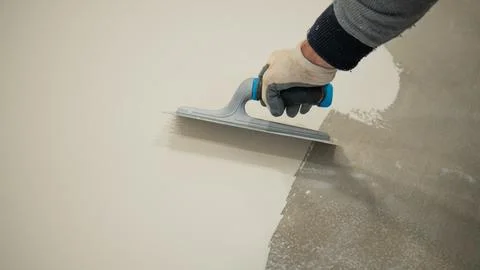 Worker Applying White Liquid Floor Coating With Roller and Trowel Stock Photos
