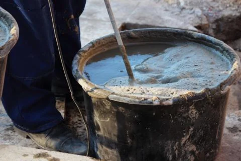 Worker are mixing cement with a tool a construction mixer for fixing the facing Stock Photos
