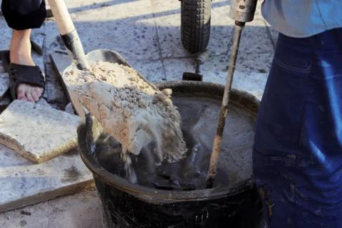 Worker are mixing cement with a tool a construction mixer for fixing the facing Stock Photos
