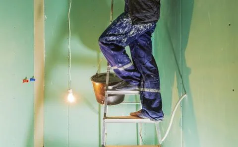 Worker are putting up the ceiling from ladder in apartment is under construction Stock Photos