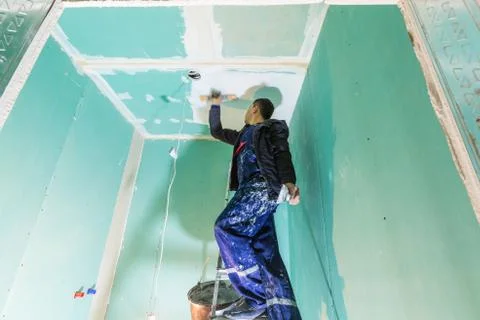 Worker are putting up the ceiling from ladder in apartment is under construction Stock Photos