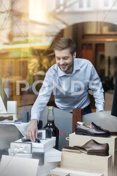 Worker arranging window display in menswear shop Stock Photos
