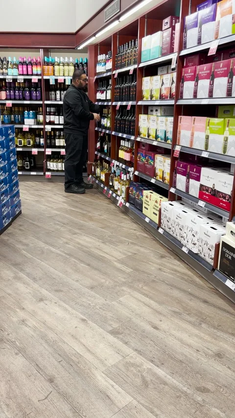 A worker arranging wine bottles on shelf at liquor store. Stock Footage 275582894