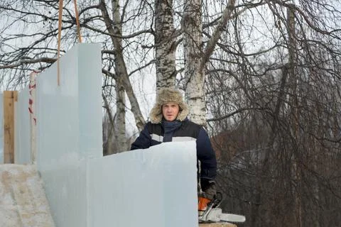 Worker assembler in blue jacket and fur hat at construction site 스톡 사진