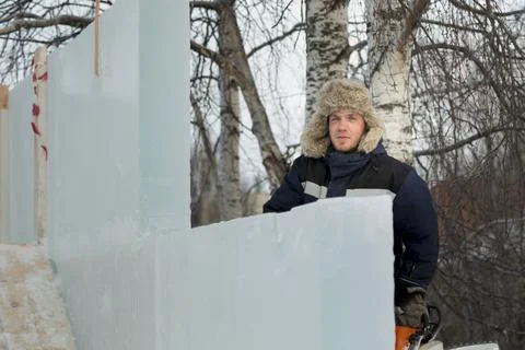 Worker assembler in blue jacket and fur hat at construction site 스톡 사진