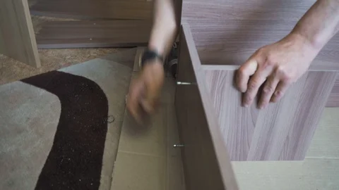 Worker assembles and twists the wooden table with a screwdriver and screws Stock Footage 108465311
