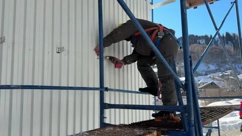 A worker assembles a building structure at a construction site. Vídeos de archivo 299602243