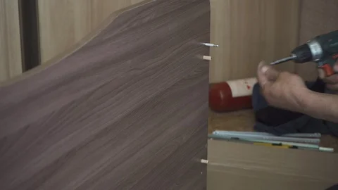 Worker assembles furniture with a screwdriver and special screws Stock Footage 108465459