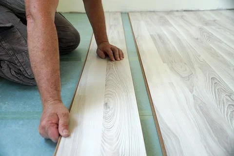 A worker assembles a laminate floor in a living room Stock Photos