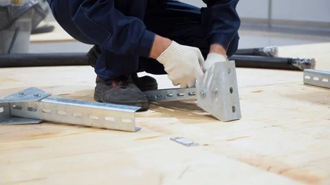 Worker assembles metal construction at factory, holds bolt with pair of pliers Stock Footage 126357313