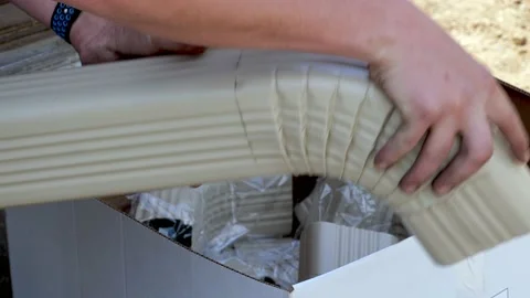 Worker assembles sections of aluminum rain gutter downspout. Stock Footage 156051303