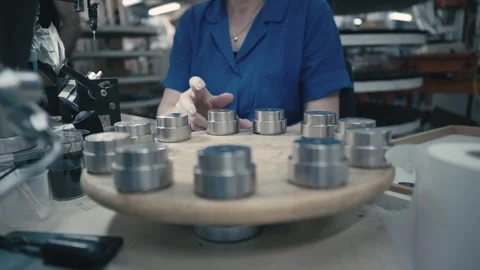 Worker assembling metal speaker parts on a rotary table inside a factory Stock Footage 320877390