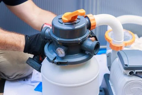 Worker assembling a sand filter system tank, equipment for cleaning swimming Stock-Fotos