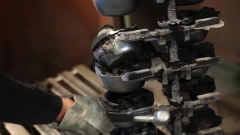 Worker assembling small cast iron pot components onto metal rack closeup Видео 345016009