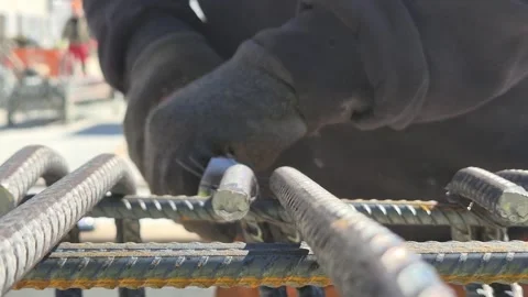 Worker assembling steel reinforcement bars on scaffolding close-up front view Vidéo 333248939