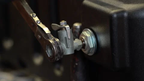 A worker in an assembly shop screws a car crane into the tank of a heavy tractor Stock Footage 148051202